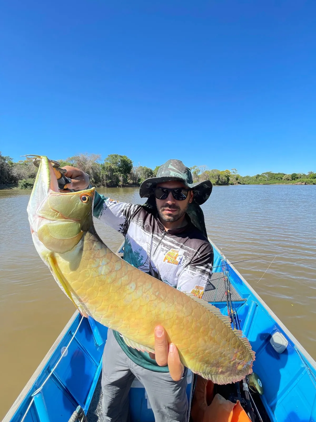 Pescador num barco segura uma aruanã