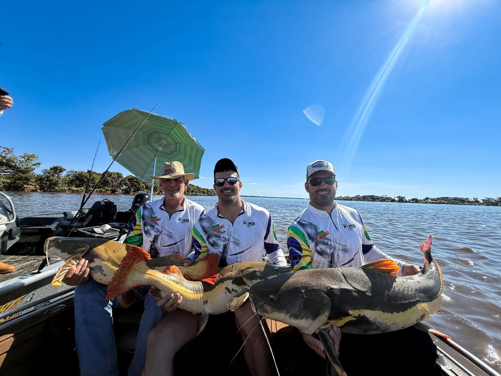 Três pescadores num barco com duas pirararas