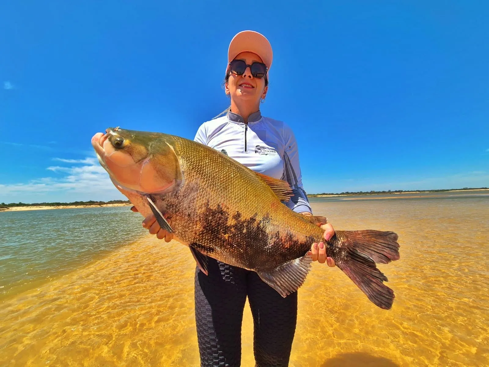 Pescadora na praia segura um tambaqui