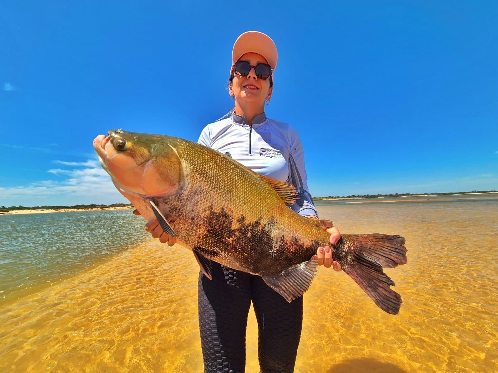 Pescadora na praia segura um tambaqui