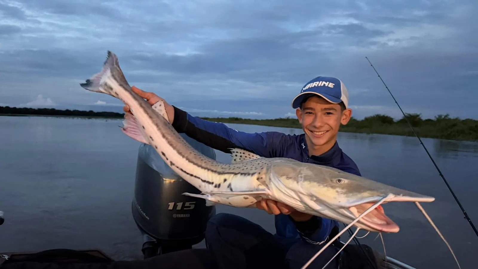 Jovem pescador num barco segura uma cachara