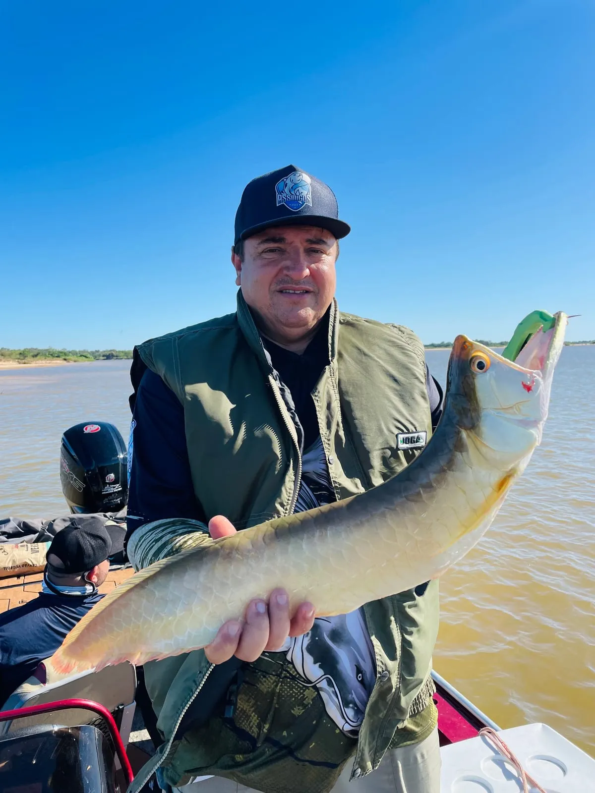 Pescador num barco segura uma aruanã