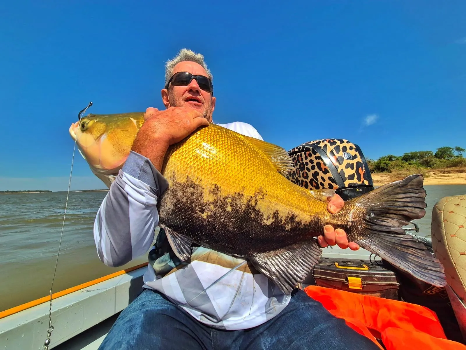 Pescador num barco segura um tambaqui