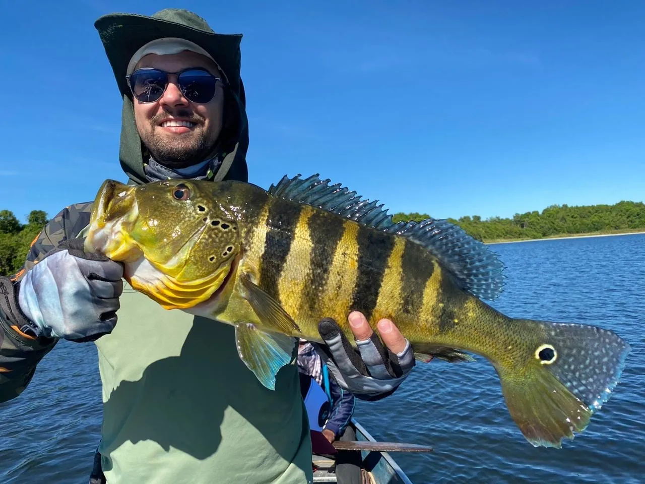 Pescador de luvas segura um tucunaré