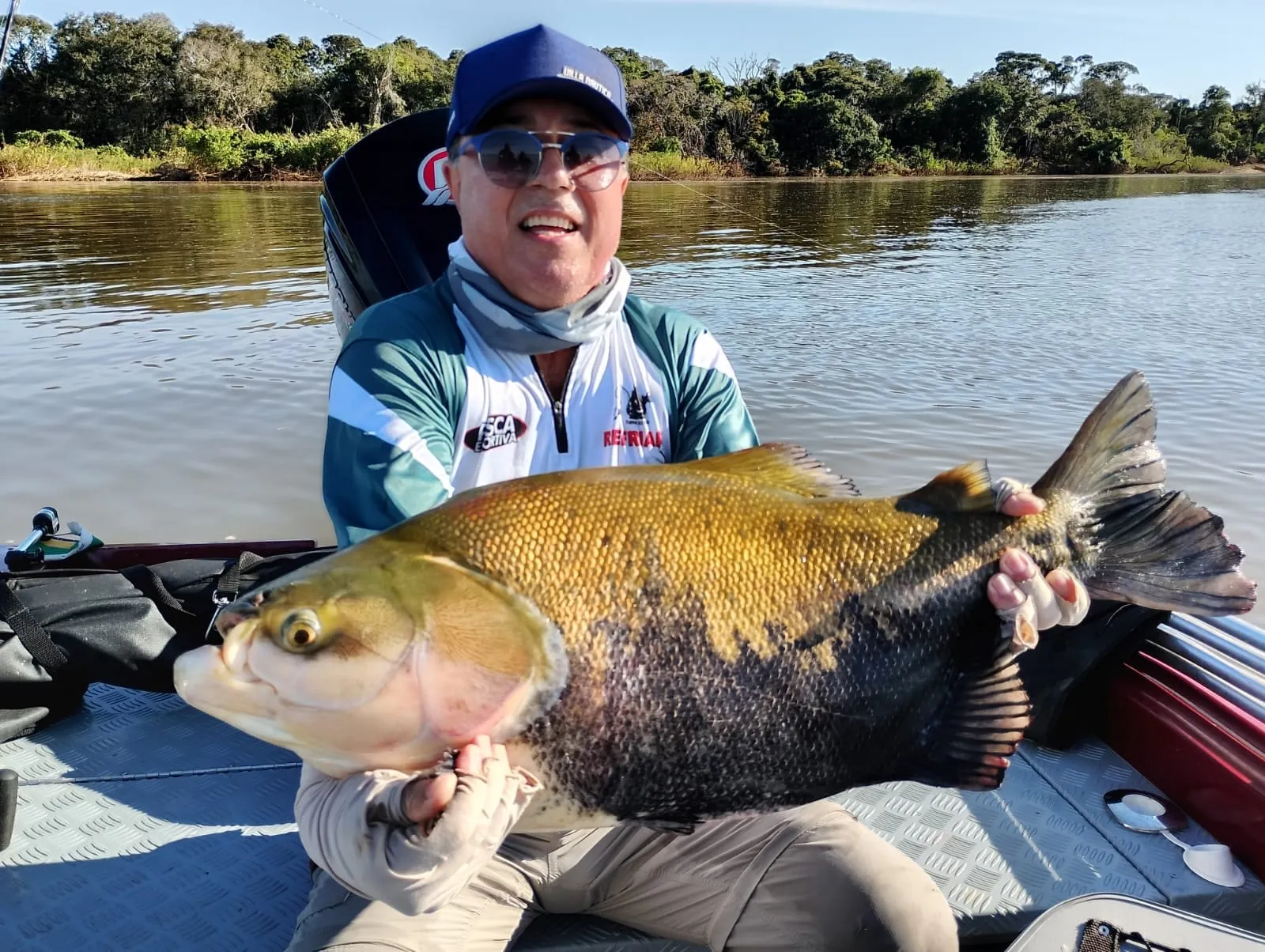 Jovem pescador num barco segura um tambaqui