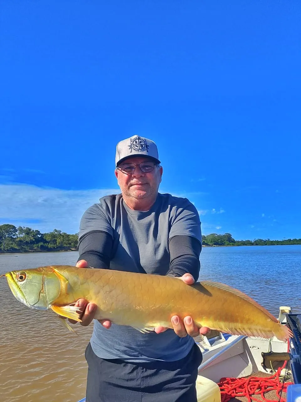 Pescador num barco segura uma aruanã