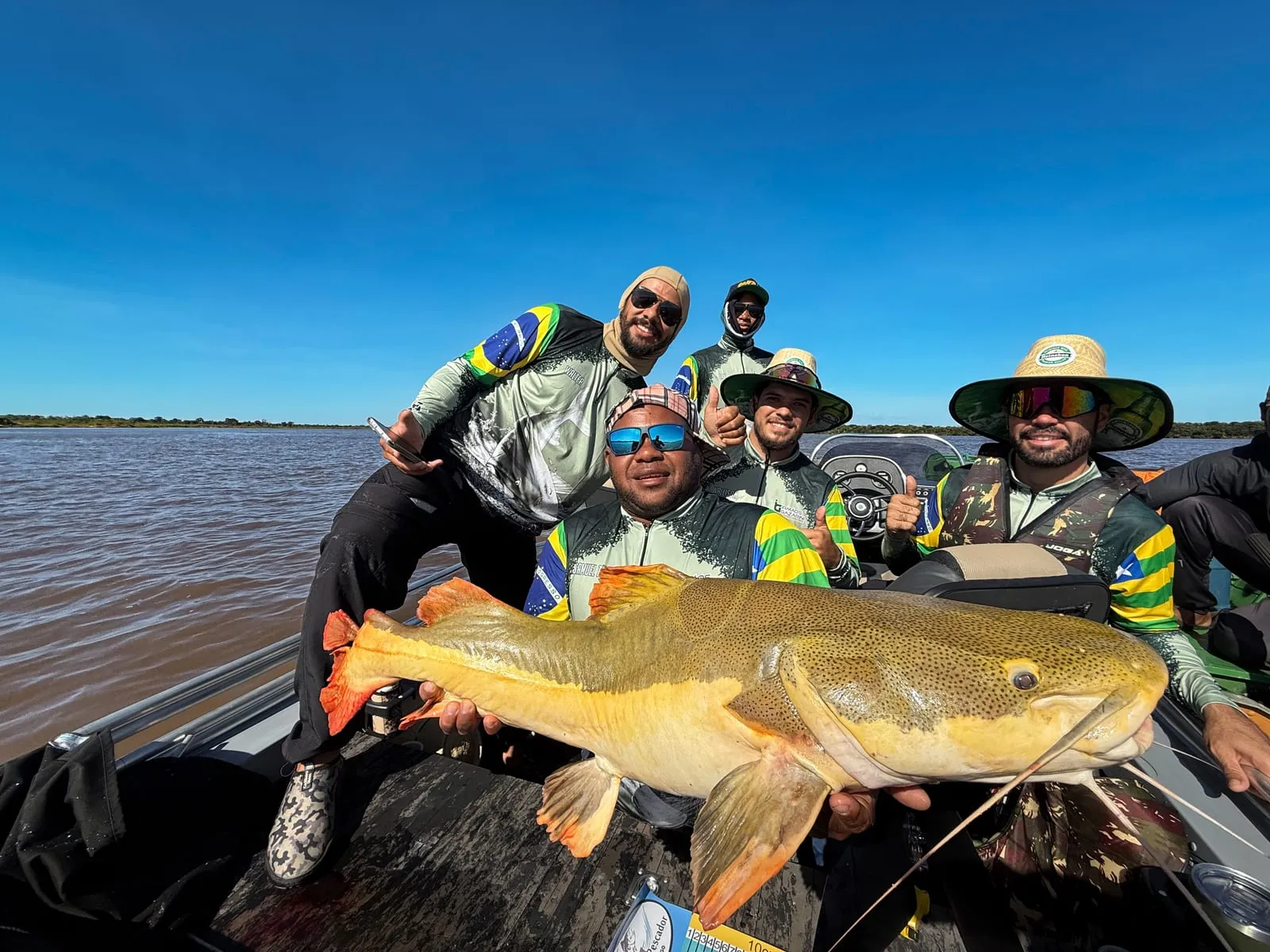 Grupo de pescadores num barco com uma pirarara