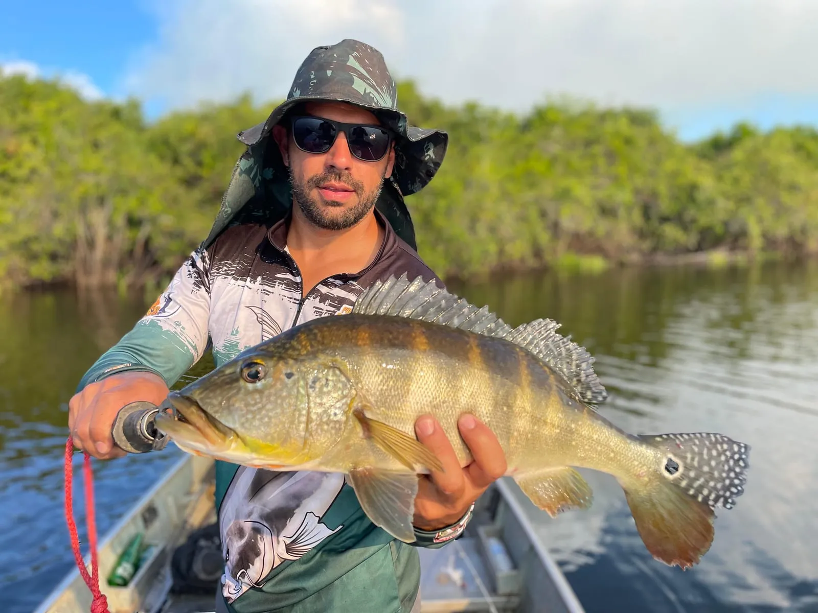 Pescador de chapéu segura um tucunaré