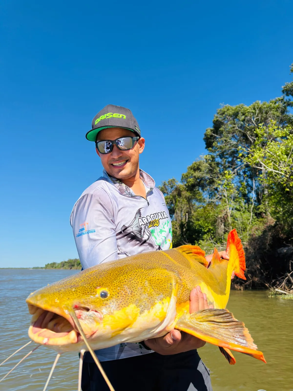 Pescador segura uma pirarara de cauda vermelha