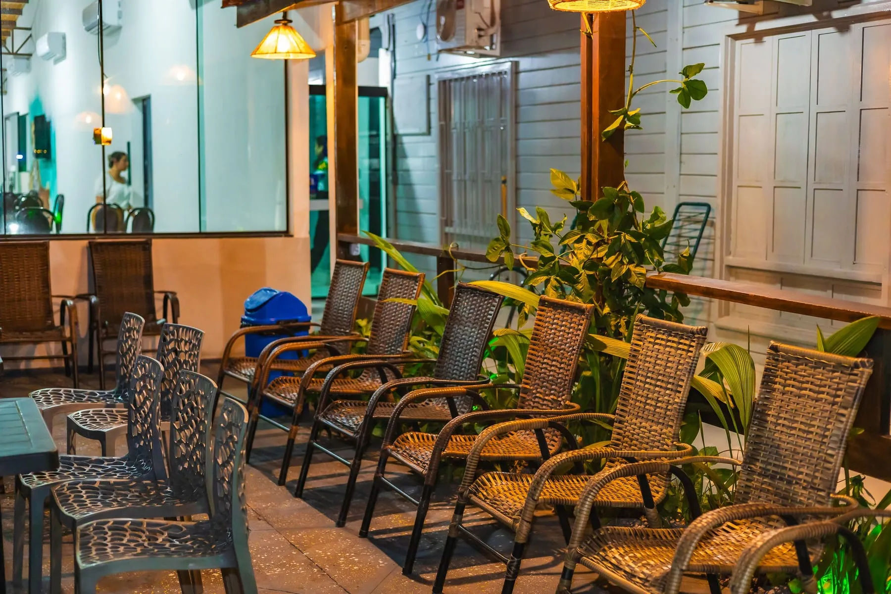 Varanda com cadeiras de fibra e plantas, iluminada à noite