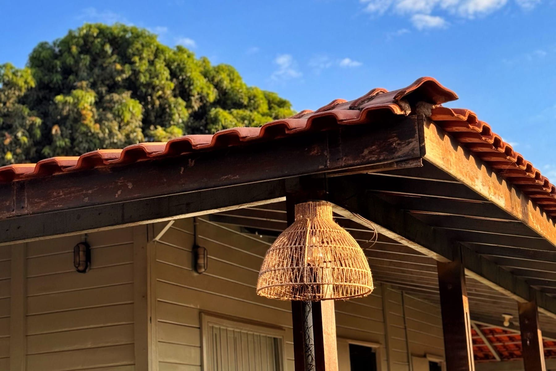 Chalé de madeira da pousada com telhado de telha e luminária de palha