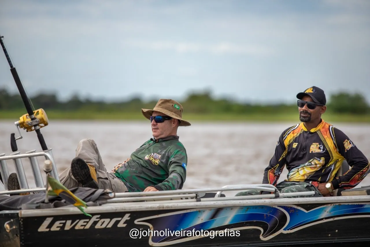 Dois pescadores num barco no Rio Araguaia, um deles sentado com a vara de pesca
