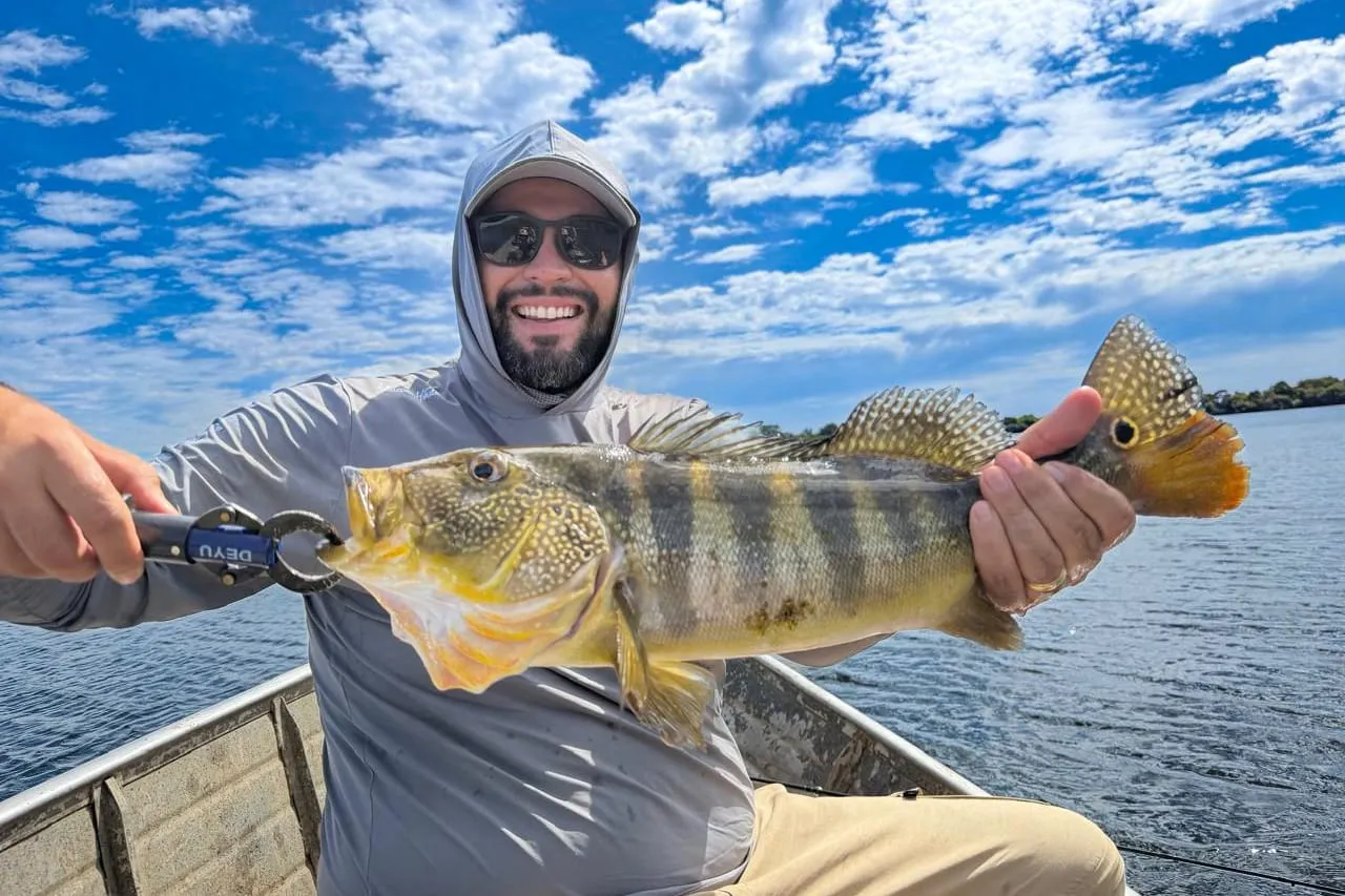 Pescador mostra um tucunaré no barco