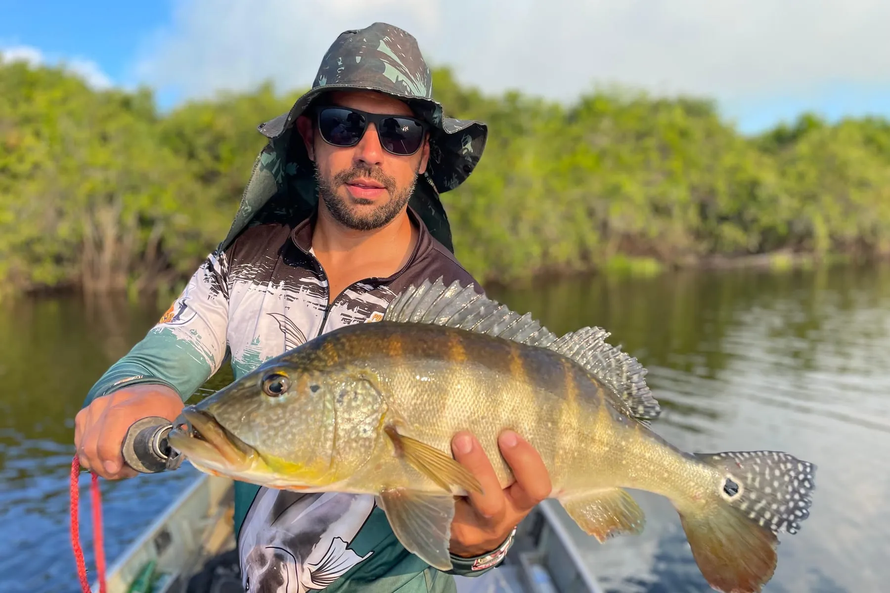 Pescador de chapéu mostra um tucunaré