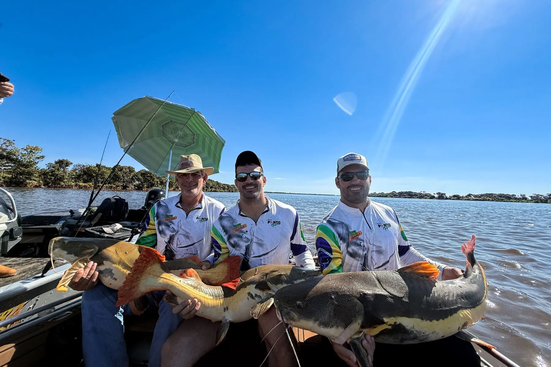 Três pescadores no barco com duas pirararas