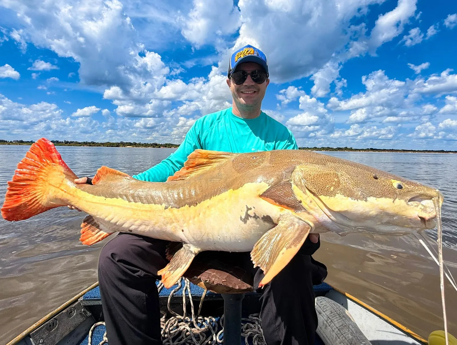 Pescador no barco segura uma pirarara no Rio Araguaia