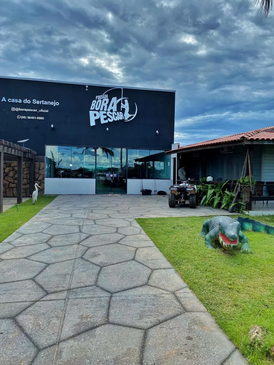 Fachada da Pousada Bora Pescar com jardim e escultura de jacaré