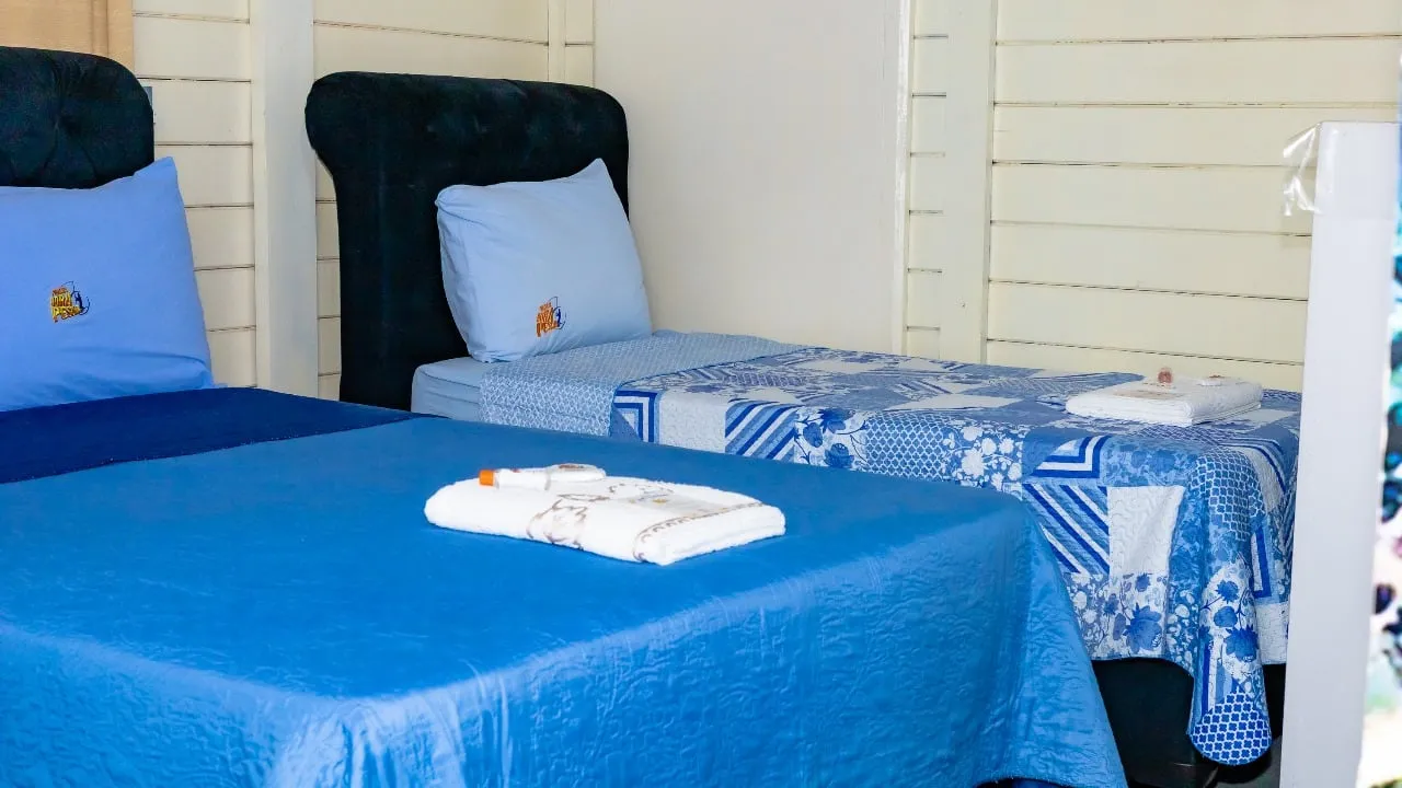 Cama de casal com roupa de cama azul e toalhas dobradas