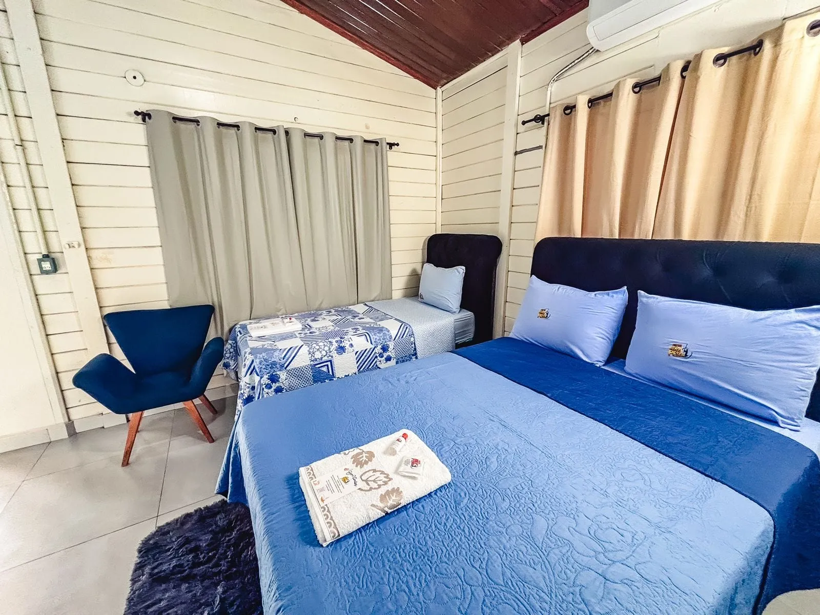 Quarto com cama de casal, cama de solteiro, poltrona e ar-condicionado