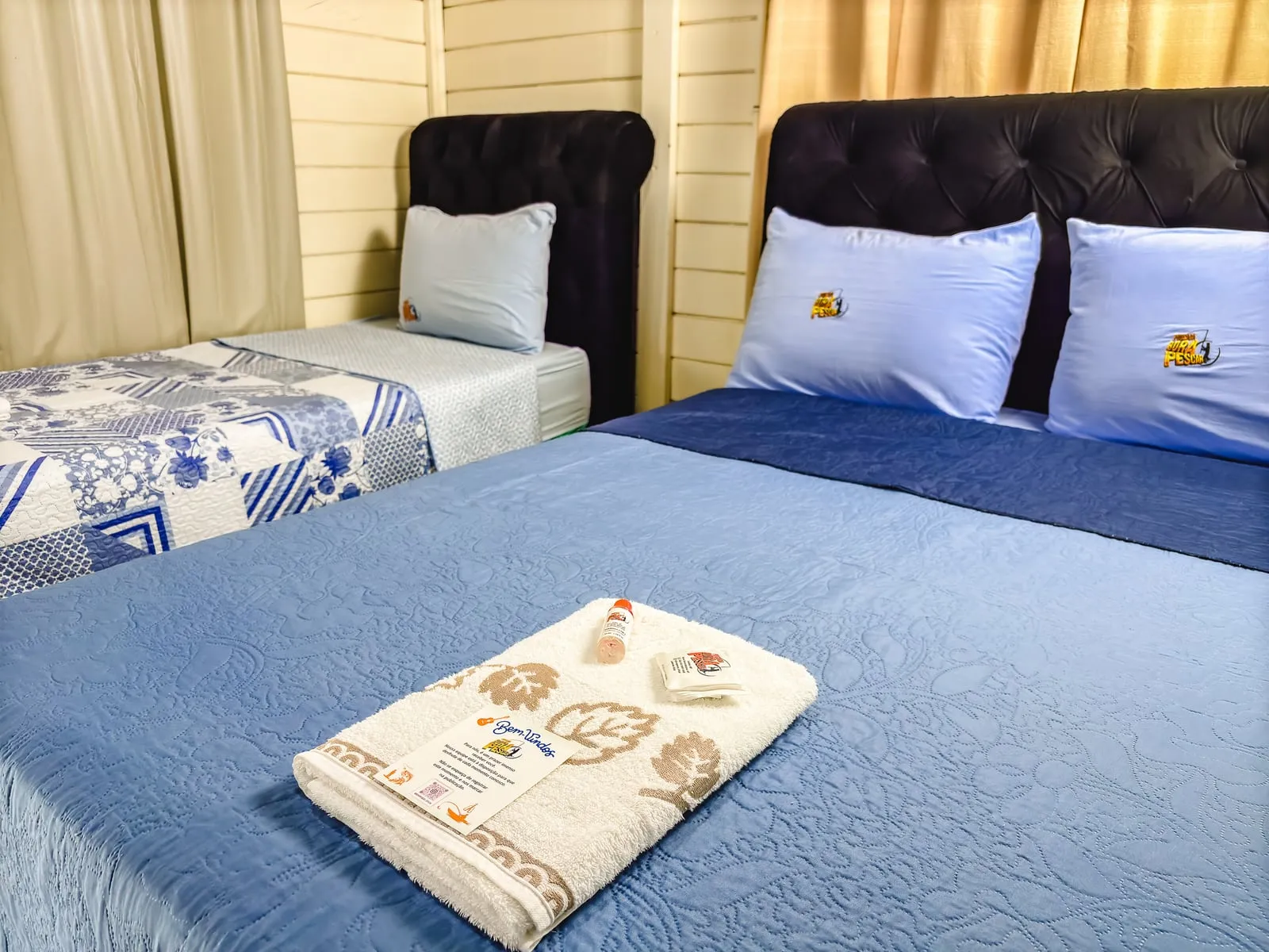 Quarto com cama de casal e cama de solteiro com roupa de cama azul