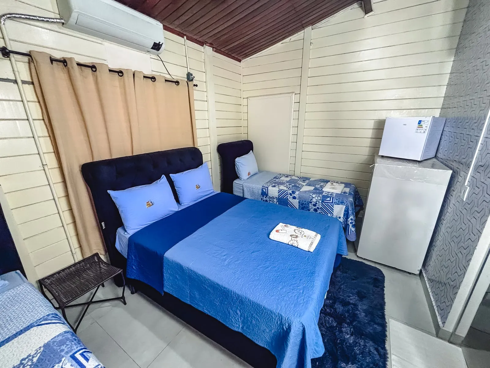 Quarto com cama de casal, cama de solteiro e frigobar