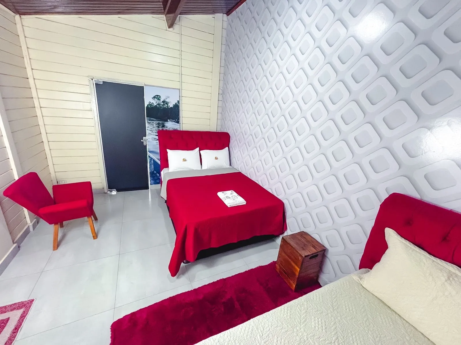 Quarto com cama de casal vermelha e poltronas